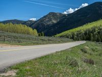 the road is paved with yellow markings and has a snowy mountain range in the background