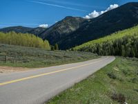 the road is paved with yellow markings and has a snowy mountain range in the background