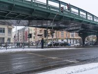 man waiting in crosswalk on snowy day near traffic lights in city center, during day