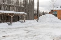 snow drifts along the sidewalk in front of a building with a shed and awning