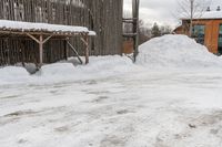 snow drifts along the sidewalk in front of a building with a shed and awning