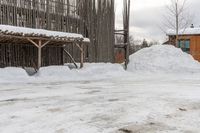 snow drifts along the sidewalk in front of a building with a shed and awning