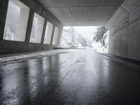 street in the middle of snowy day under highway bridge and a ramp with one red stop sign