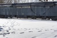 tracks and footprints in snow leading to a dark blue traincarck with the word york durham written on it