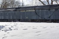 tracks and footprints in snow leading to a dark blue traincarck with the word york durham written on it