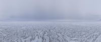 a lone person standing on the shore of an ocean covered in ice and snow with mountains in the distance