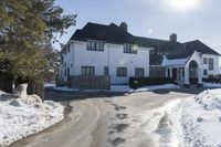 a long driveway is lined with snow leading to the main house of the estater