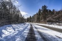 a road in the middle of a snowy forest covered with trees and snow covered ground