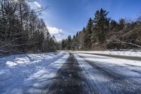 a road in the middle of a snowy forest covered with trees and snow covered ground