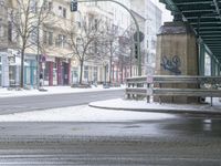 a man stands on the side of the road under a bridge in the snow with a newspaper