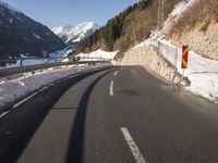 the side of a very narrow, icy highway with snow on the ground and mountains in the background