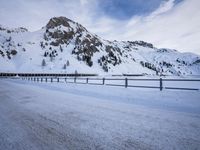 a snow covered highway going down a hill side next to a mountain range that is on the opposite side