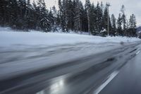 a blurry photograph of a snowboarder in the road surrounded by trees and woods