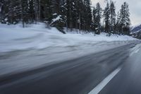 a blurry photograph of a snowboarder in the road surrounded by trees and woods