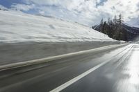 a man on skis is skiing down the road near the mountains with a sky background