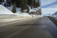 a person is riding down a snowy highway in the mountains outside of the city, as well as an animal in the distance
