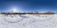 the sun is shining in the distance behind some tracks on a snowy hill with trees and grass