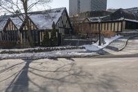 houses in the snow on a city street with trees on either side of them and a car passing by