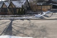 houses in the snow on a city street with trees on either side of them and a car passing by