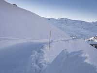 a hill covered in snow next to a road with a red stop sign by it