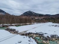 a snowy, wintery landscape of rocks and mountains with a wooden bridge crossing over