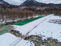 a snowy, wintery landscape of rocks and mountains with a wooden bridge crossing over