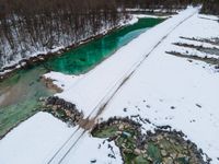 a snowy, wintery landscape of rocks and mountains with a wooden bridge crossing over