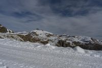 a person with skis walking across a snowy hill towards a mountain top covered in snow