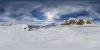 there is snow covering the ground, and there are mountain tops in the background under a cloud