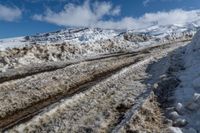 snow piled down on a snowy road in the mountains of the mountainside and a person standing next to it