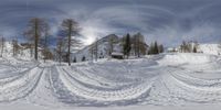 a snowy mountain has trees and clouds on it, near a building and skis