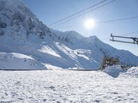 a mountain covered with snow and power lines in the distance, with the sun in the air