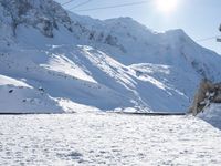 a mountain covered with snow and power lines in the distance, with the sun in the air