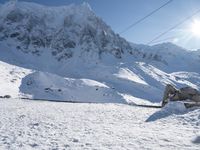 a mountain covered with snow and power lines in the distance, with the sun in the air