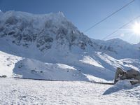 a mountain covered with snow and power lines in the distance, with the sun in the air