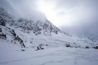 a skier is standing on a slope of snow, near rocks and mountain peaks with the sky in the background