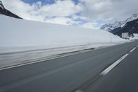 a snow covered mountain is seen from the side of a car's windshield as the snow drifts along it