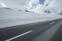 a snow covered mountain is seen from the side of a car's windshield as the snow drifts along it