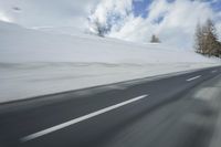 a snow covered mountain is seen from the side of a car's windshield as the snow drifts along it