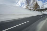 a snow covered mountain is seen from the side of a car's windshield as the snow drifts along it