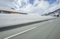 a snow covered mountain is seen from the side of a car's windshield as the snow drifts along it