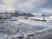 a bunch of snow piled up on the ground near some buildings in the mountains behind it