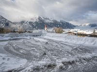 a bunch of snow piled up on the ground near some buildings in the mountains behind it