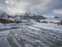a bunch of snow piled up on the ground near some buildings in the mountains behind it