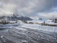 a bunch of snow piled up on the ground near some buildings in the mountains behind it