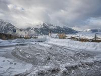 a bunch of snow piled up on the ground near some buildings in the mountains behind it