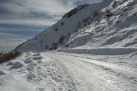 a snowy mountain top with tracks in the snow on skis next to a road