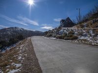 Snowy mountain landscape with concrete road and sunny sky