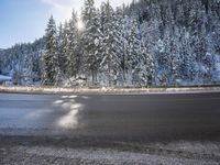 a man stands next to a snow covered forest in the road while a car drives past