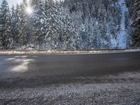 a man stands next to a snow covered forest in the road while a car drives past